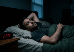 man lies awake in bed