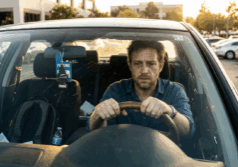 man sits in his car in a parking lot